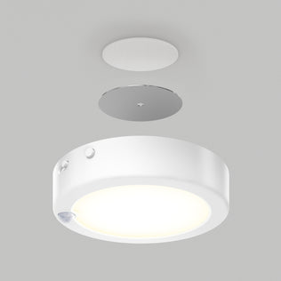 The Artika Accent under cabinet LED light 3CCT is shown disassembled with its mounting plate and a small circular cover above, all set against a plain gray background.