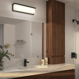 Modern bathroom with a marble countertop, wooden cabinets, black faucet, soap dispensers, a vase with greenery, large mirror, and a rectangular wall-mounted light fixture above the mirror.