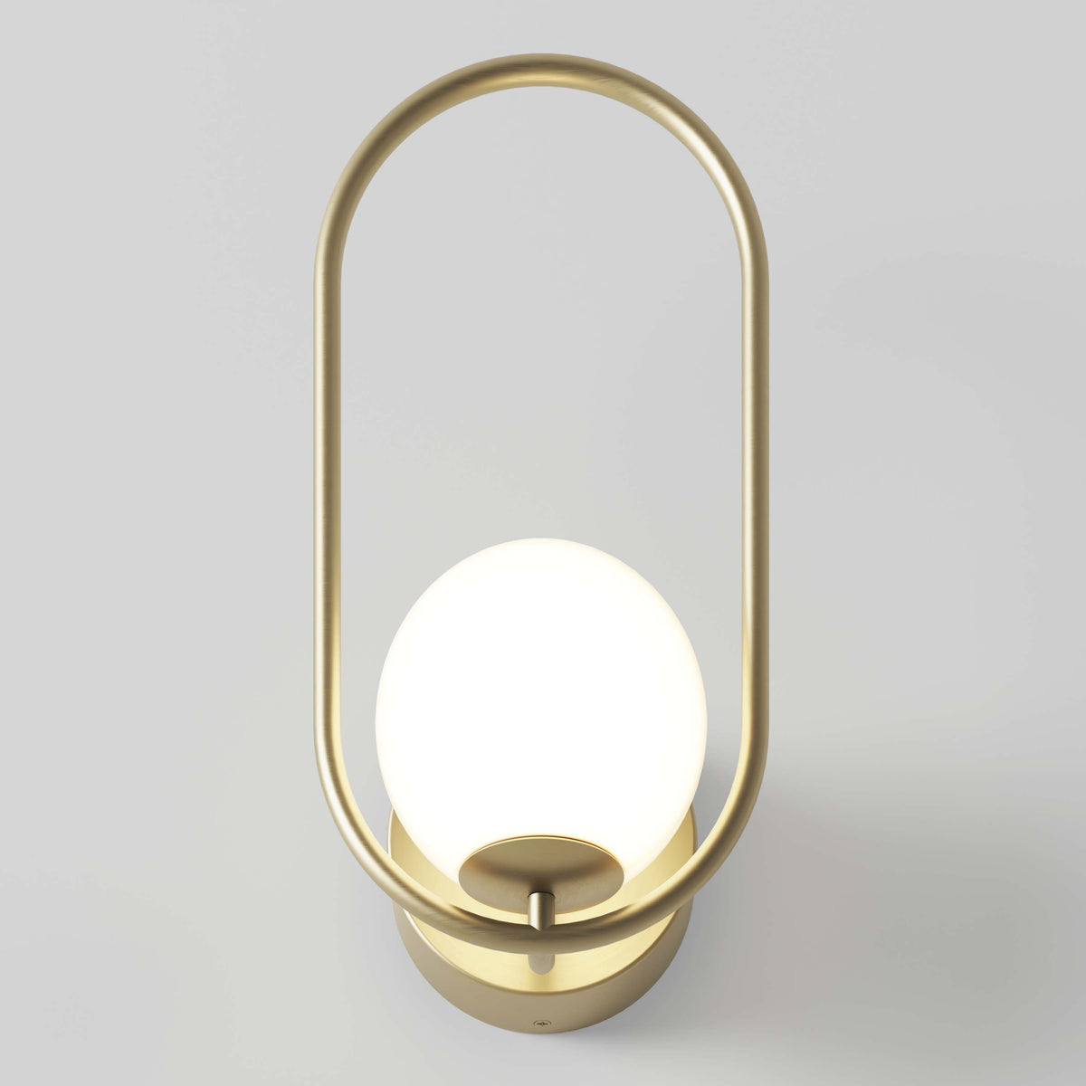 The Artika Bloom LED Sconce 3 CCT features a modern gold metal oval frame with a round, glowing white bulb at its center, shown mounted on a light-colored wall.