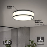 A round, modern ceiling light with a black finish is mounted on a white ceiling. Highlights include energy efficiency, integrated LED, and a 3-year warranty. A plant and a mirror are partially visible in the room below.