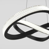 A modern, sculptural LED chandelier with interlocking black rings featuring textured, illuminated surfaces, suspended by thin wires against a light gray background.
