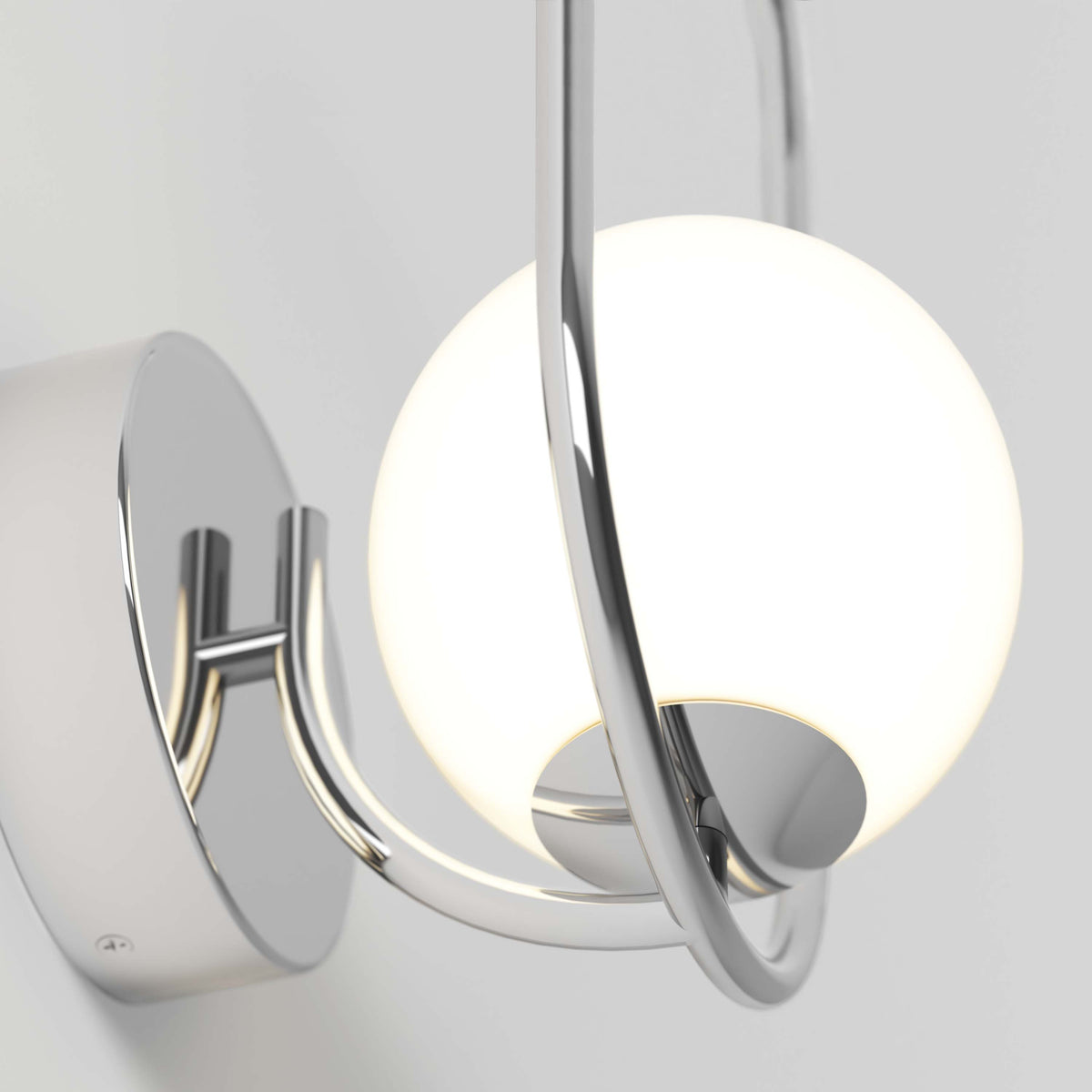 The Artika Bloom LED Sconce 3 CCT features a round white glass globe held by curved chrome arms on a circular chrome base, giving any light gray wall a modern touch.