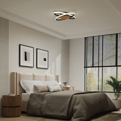 A modern bedroom features a beige upholstered bed, neutral bedding, two abstract framed artworks, a round wood nightstand, large windows with blinds, and the Artika Atomic 15 in. LED flush mount light (5 CCT) as a unique ceiling fixture.