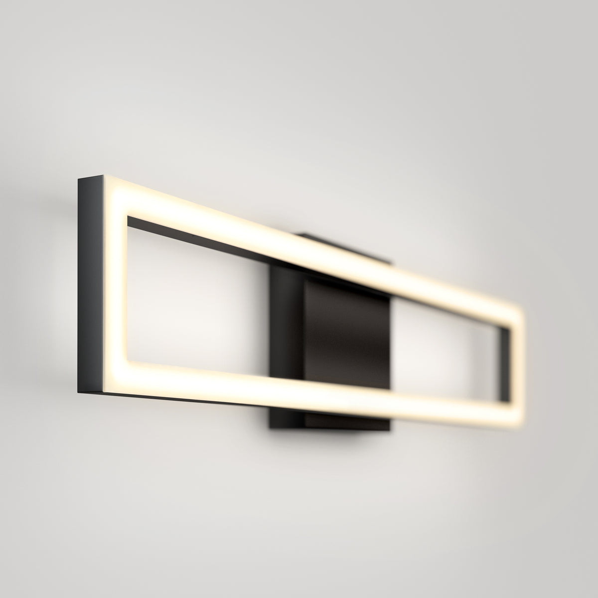 A modern wall-mounted rectangular LED light fixture with a black base and a glowing rectangular frame, set against a plain light gray wall.