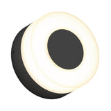 A round, modern wall light fixture with a black center and base, surrounded by a glowing white circular ring, viewed at an angle on a white background.