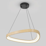 A modern, oval-shaped pendant light with a wooden finish hangs from the ceiling by three thin black cords, emitting a soft white glow.