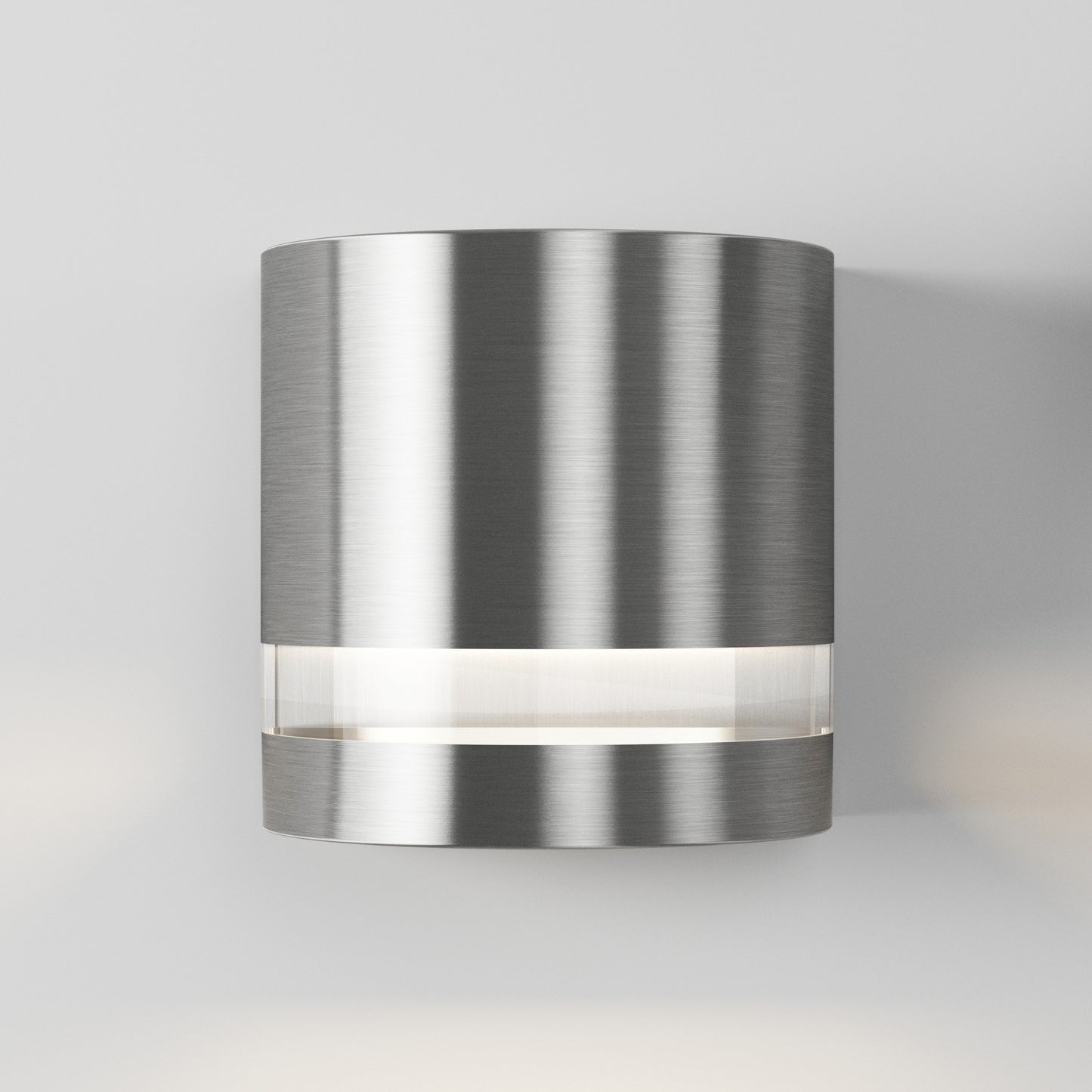 The Artika Valor Round LED indoor-outdoor wall light features a modern cylindrical design in brushed metal with a horizontal frosted section that emits a soft glow, shown mounted on a plain white wall.