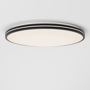 The Artika Athos 21 in. LED flush mount light, featuring a modern design with black and white layered edges, is installed on a plain white ceiling and emits a soft, diffused glow. Includes remote control for convenience.
