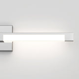 A modern rectangular wall-mounted LED light fixture emits a soft white glow against a plain light gray wall.