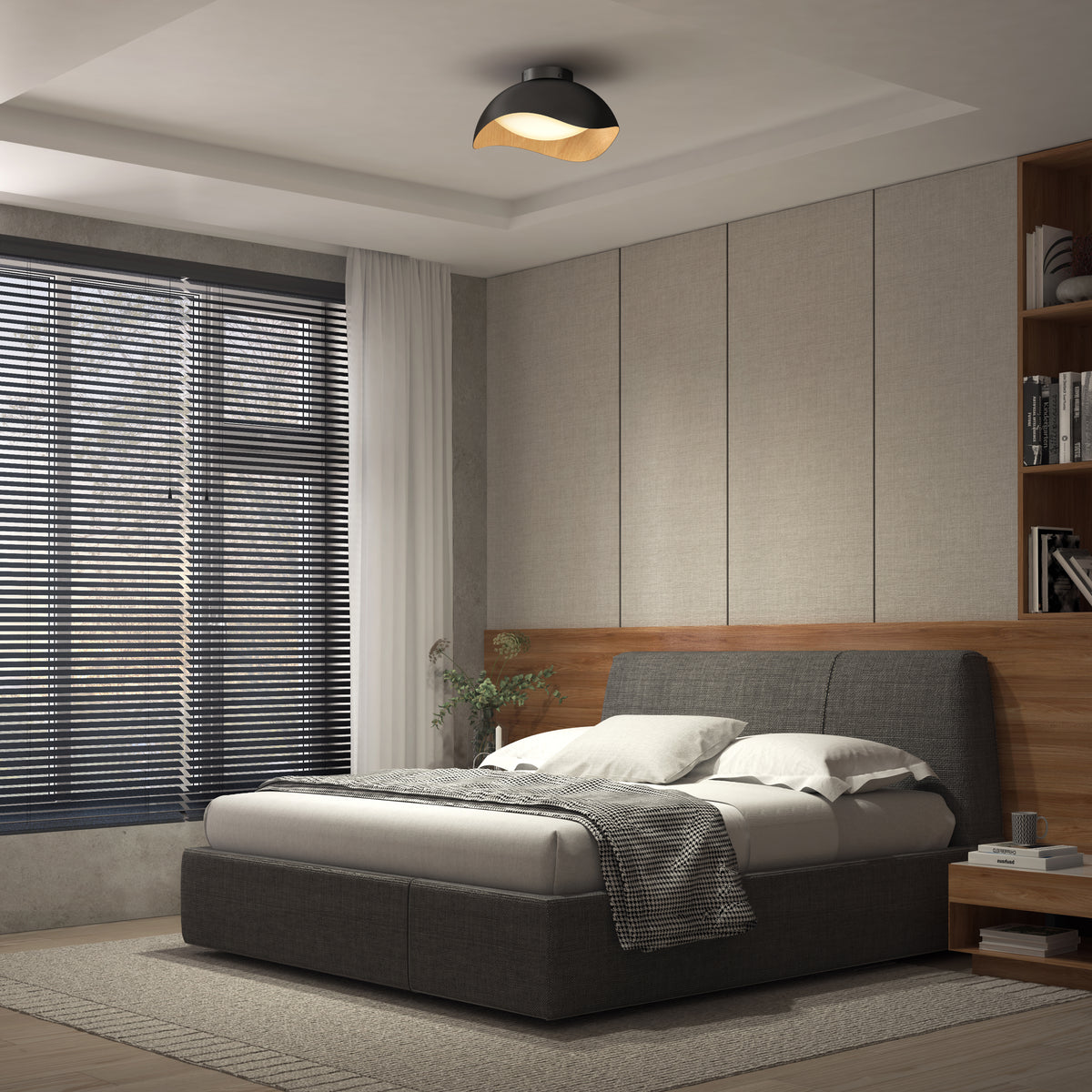 A modern bedroom with a grey upholstered bed, white and grey bedding, wood-paneled wall accents, large window with black blinds, built-in shelves, and a black ceiling light. Natural light brightens the room.