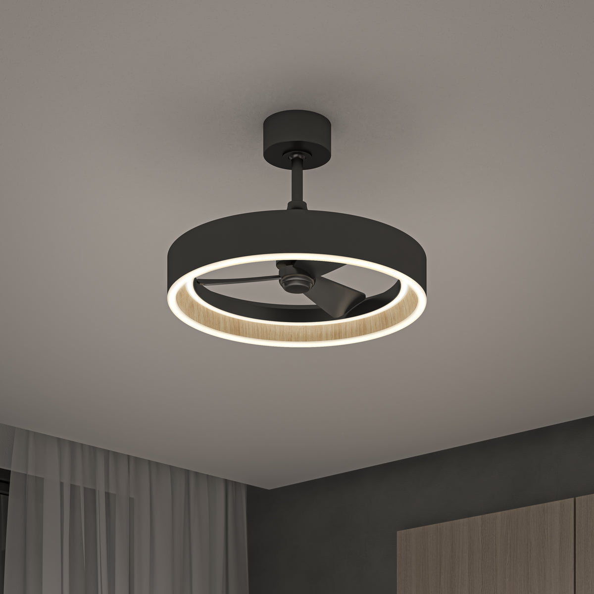 A modern ceiling fan with a circular LED light and black housing is mounted on a white ceiling. The room features a curtain and a portion of a wooden cabinet.