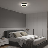 Modern bedroom with a gray accent wall, neatly made bed with neutral bedding and pillows, a round ceiling light, white built-in wardrobes, a bedside table, and a vase with dried flowers.