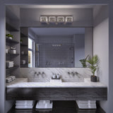Modern bathroom with a large mirror, double sink with marble countertop, wall-mounted faucets, shelves with neatly folded towels, a potted plant, and a glass-enclosed shower in the background.