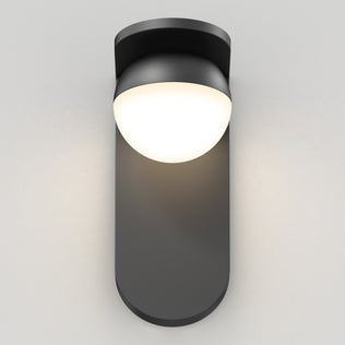 The Artika Bloom indoor-outdoor LED wall light 3 CCT features a modern design with a matte black base and rounded white dome, casting a soft, warm glow against light gray walls.
