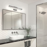 Modern bathroom with a white vessel sink on a black marble countertop, a large mirror above with a sleek light fixture, a glass shower, a towel hanging, and a small plant for decoration.