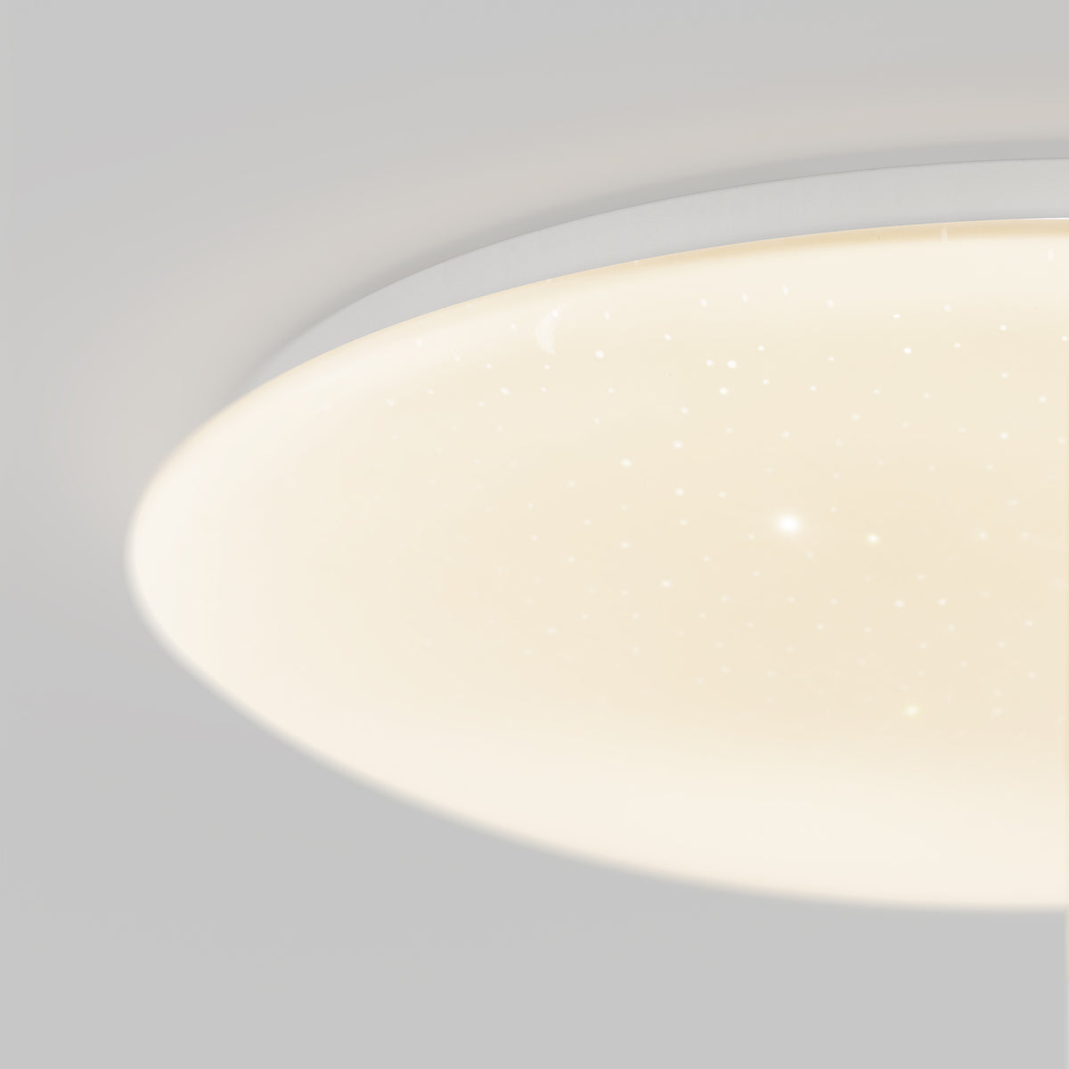 Close-up of a round, ceiling-mounted LED light fixture with a smooth, white surface illuminated, featuring small dots that resemble stars or a starry sky effect.