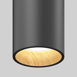 A close-up of the Artika Alton mini LED pendant light 5 CCT shows its modern cylindrical design with a matte black finish and light wood-textured inner rim, emitting a soft white glow against a plain gray background.