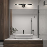 A modern bathroom vanity with a rectangular mirror, a white vessel sink, a black faucet, a small plant, wood cabinetry, and a sleek, curved wall light above the mirror.