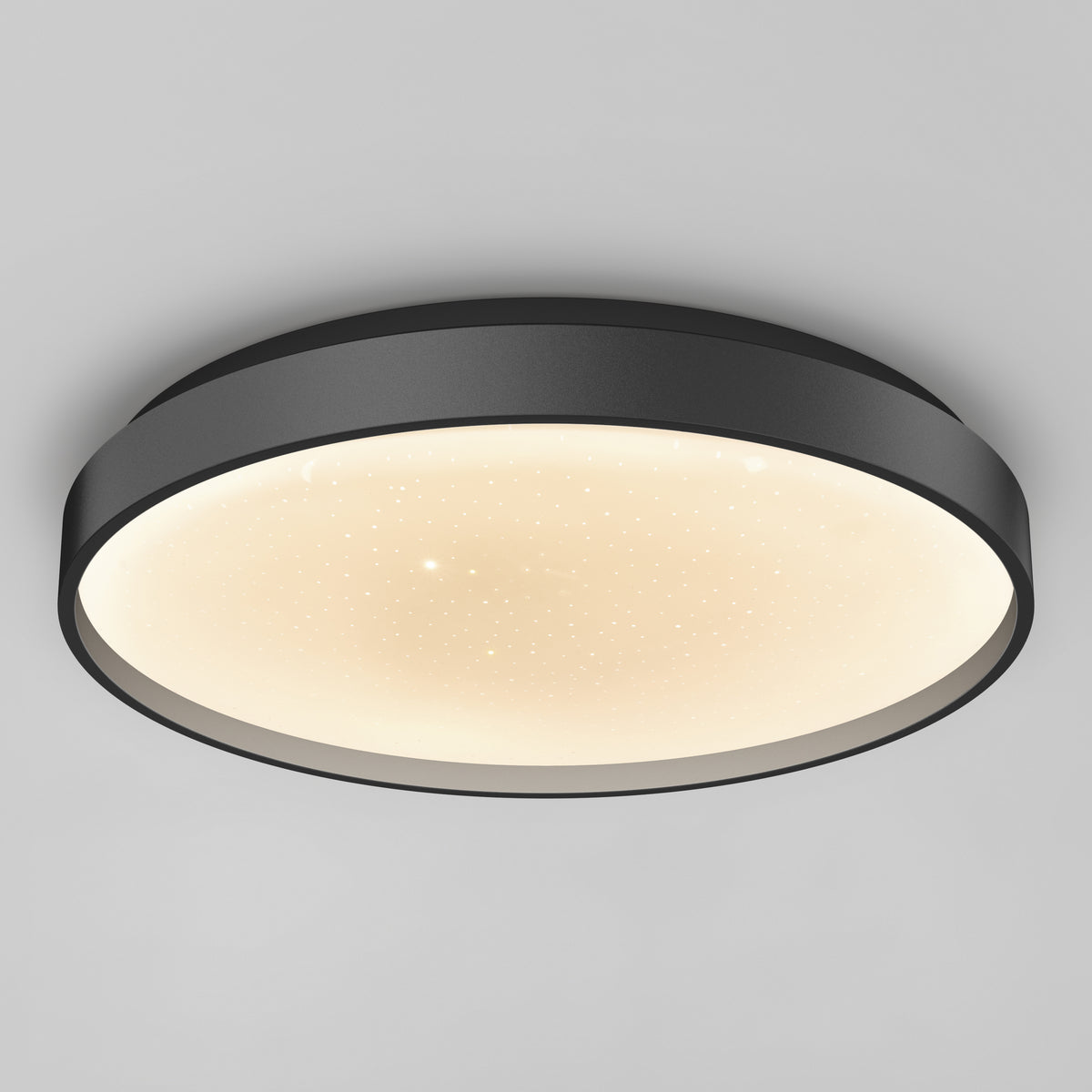 The Artika Celestia 15 in. modern LED flush mount light features a black frame, softly glowing white star-patterned diffuser, and comes with a remote, shown mounted on a plain light gray ceiling.