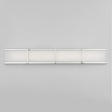 A modern, rectangular wall light fixture with four frosted glass panels framed in silver metal, mounted horizontally on a plain light gray wall.