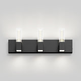 A modern black wall-mounted light fixture with three rectangular LED lights, evenly spaced, each emitting a bright glow upward and downward against a plain light gray background.