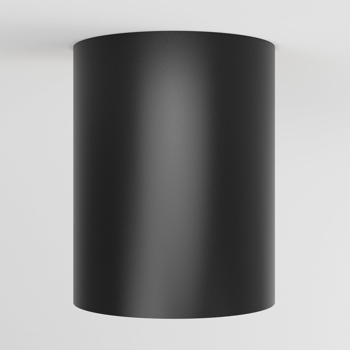 A black cylindrical light fixture is mounted on a white ceiling, viewed from below.
