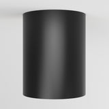 A black cylindrical light fixture is mounted on a white ceiling, viewed from below.