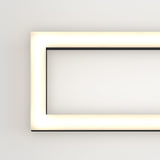A glowing rectangular light fixture with rounded corners is mounted on a plain white wall, emitting a soft, even light. Only the left half of the fixture is visible in the image.