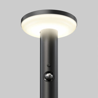 The Artika Urbia Solar LED Bollard features a black pole, round light, motion sensor button, and is shown on a plain gray background.