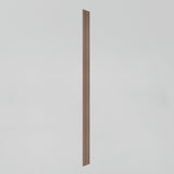 A single thin, vertical wooden slat with grooves, centered against a plain, light grey background.