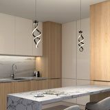 Modern kitchen with light wood and white cabinetry, marble countertops, and backsplash. Two contemporary spiral pendant lights hang above the island, which has a cup, plate, and magazine on it. Two gray chairs are visible.