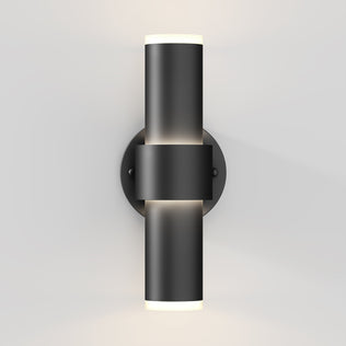 The Artika Dani modern LED indoor-outdoor wall light 5 CCT features a sleek cylindrical black design on a round base, emitting light from both the top and bottom against a light gray wall.