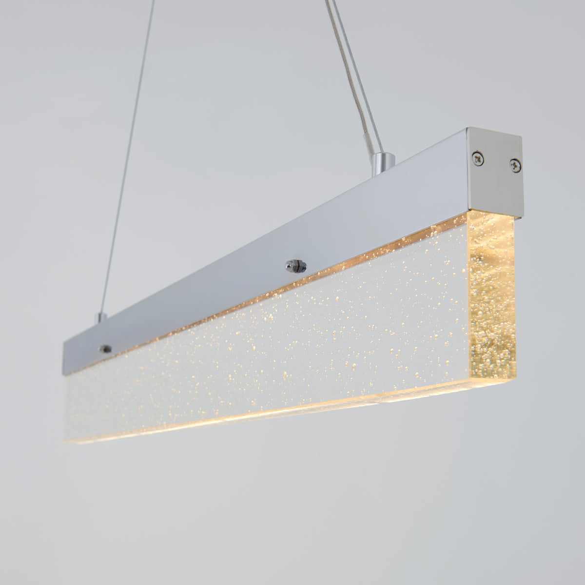 A modern rectangular pendant light with a frosted, glittery acrylic shade and a silver metal frame, suspended by two cables against a plain light gray background.