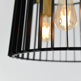 Close-up of a modern black metal light fixture with exposed filament bulbs glowing warmly, viewed through vertical metal bars against a plain, light background.