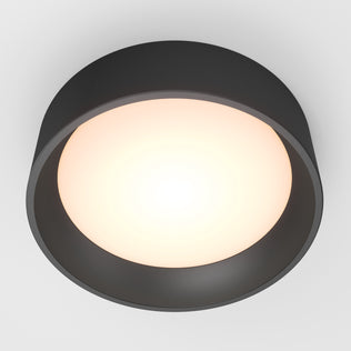 The Artika Alton LED flush mount features a modern round design with a black outer rim and glowing white center, emitting soft, even light against the ceiling.