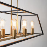 A close-up of a modern rectangular chandelier with exposed Edison bulbs and gold lamp holders, framed by a black metal geometric structure against a light-colored wall.