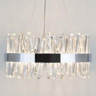 The Enchanted LED pendant light by Artika features a circular chrome frame with angled crystal prisms, suspended by two thin wires, casting a bright warm glow against a neutral background.