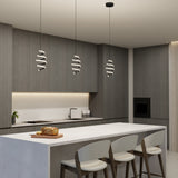 A modern kitchen with gray cabinets, a white island with three bar stools, spiral pendant lights, a built-in oven, and a loaf of bread on a cutting board on the counter.