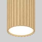 A cylindrical ceiling light fixture with a ribbed, light wood texture and a glowing white circular base, set against a plain gray background.