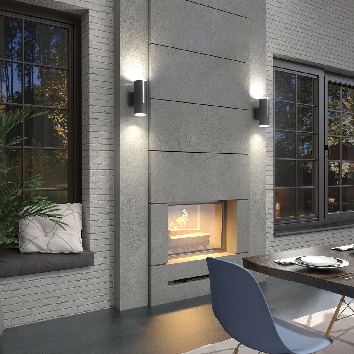 Modern living room with a concrete fireplace and two wall sconces above it, a window seat with cushions and a plant, large windows, and a dining table with a blue chair in the foreground.