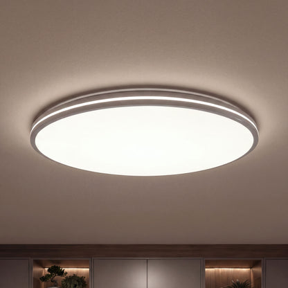 Artika’s GLOW 30 in. LED Flush Mount Ceiling Light with 5 CCT and remote shines over wooden shelves and plants in a modern room.