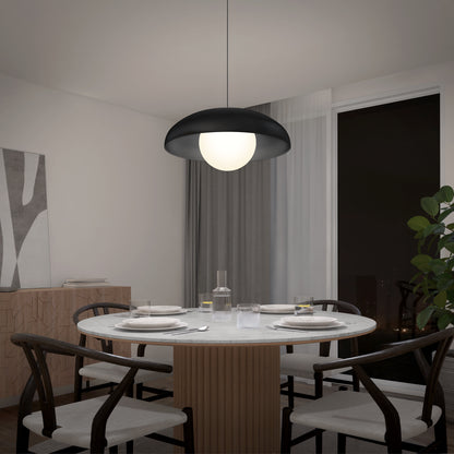 A modern dining room features a round table for four, black chairs, a large curtained window, and the Artika Boden LED modern mid-century pendant light (3 CCT) overhead. A plant and sideboard complete the stylish setting.