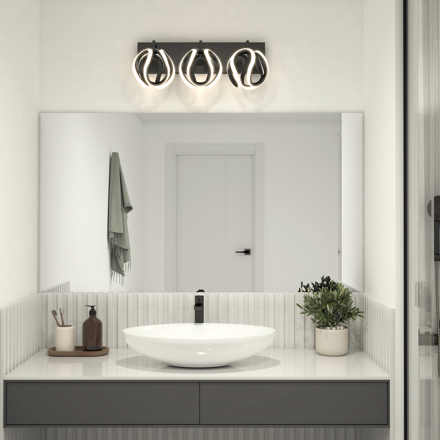 Modern bathroom featuring a round vessel sink, black faucet, large mirror, and Artika’s Vivaldi LED contemporary vanity light (3 CCT) above. Countertop holds a plant, soap dispenser, bottles; towel hangs on the wall.