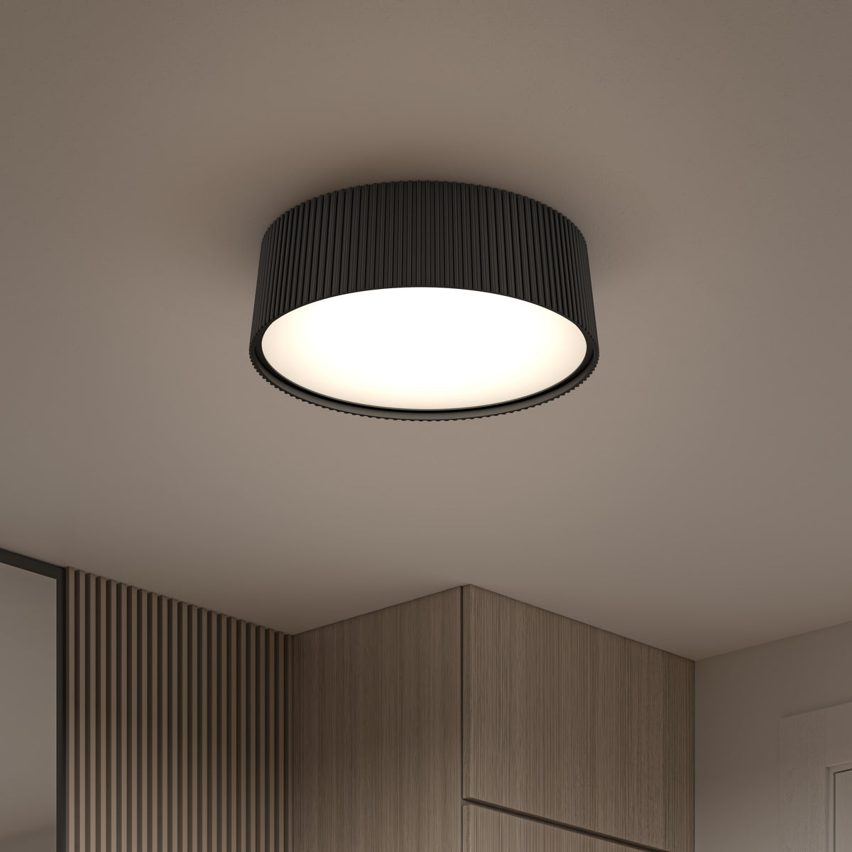 The Artika Groove 13 in. LED modern flush mount light with a ribbed black finish is installed on a white ceiling, casting bright illumination over a room featuring light wood paneling and cabinetry.