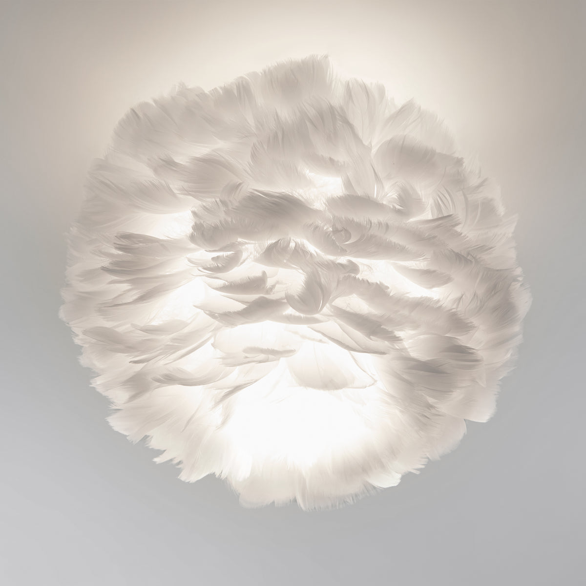 A spherical white feather lamp glows softly against a neutral background, creating a cloud-like, ethereal appearance with diffused light and delicate feather textures.