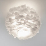 A spherical white feather lamp glows softly against a neutral background, creating a cloud-like, ethereal appearance with diffused light and delicate feather textures.