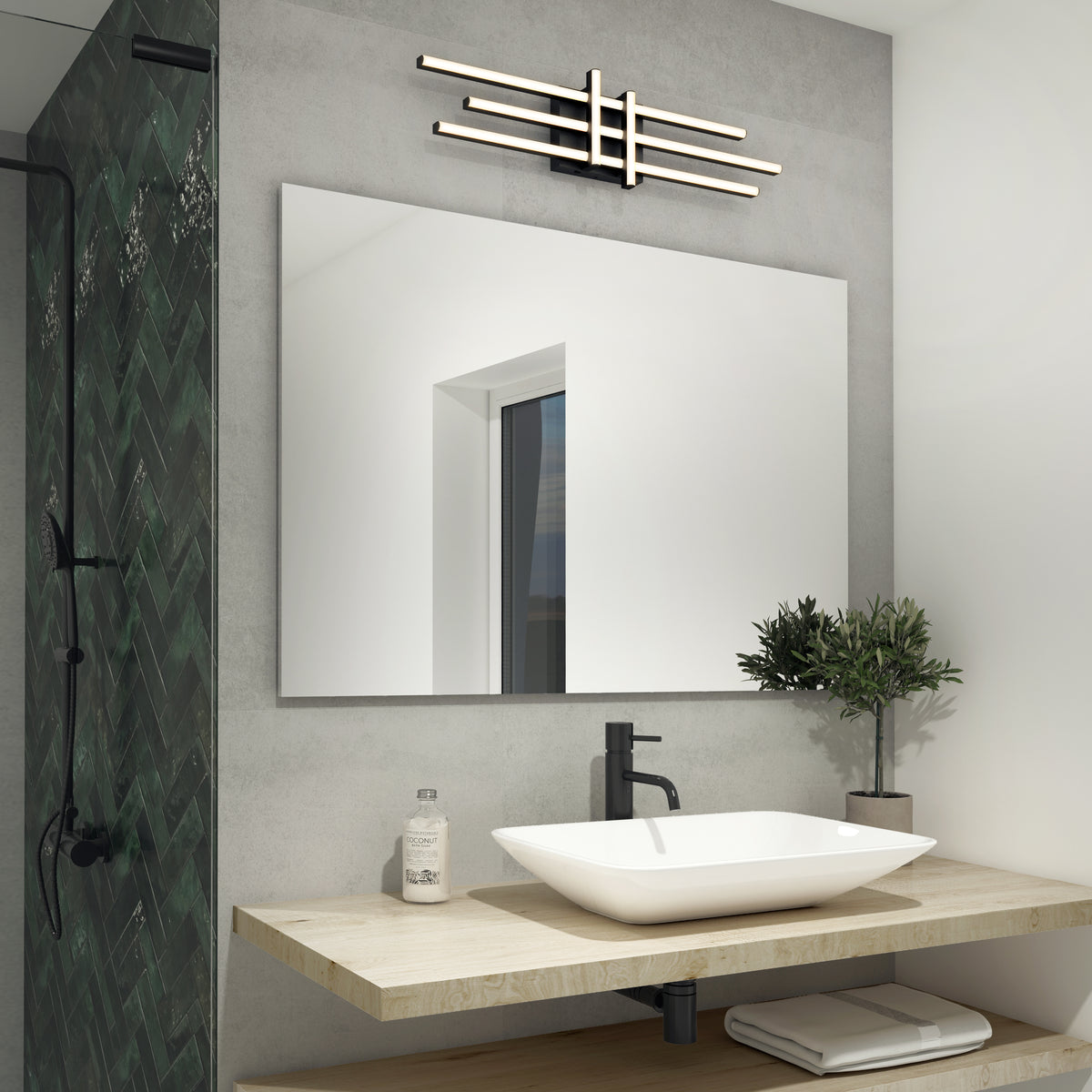 Modern bathroom with a vessel sink on a wooden floating vanity, a black faucet, a small potted plant, soap dispenser, large mirror, geometric wall sconce, and a green herringbone-tiled shower on the left.