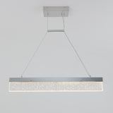 A modern rectangular pendant light fixture with a metallic frame and sparkling bubble-like details hangs from the ceiling by two thin cables. The light is illuminated against a plain white background.