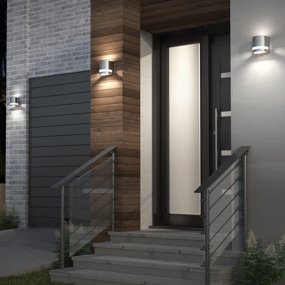 Modern front door entryway with wooden and gray brick walls, illuminated by three sleek wall-mounted lights, and metal railings on stairs leading up to the entrance.