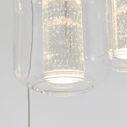 Close-up of the Artika Champagne Globe 4-light LED pendant, featuring a modern glass design with tiny bubbles in the inner cylinder, illuminated and glowing against a plain white background.